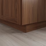 Donkerhouten keukenkastplint op lichte houten vloer, wat zorgt voor een nette afwerking en ondersteunende structuur.