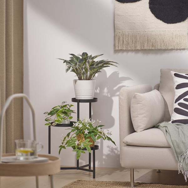 Moderne woonkamer met plant, fauteuil, kussens met patroon, bijzettafel en kunst aan de muur.