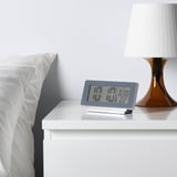 Nachtkastje op nachtkastje, led-display met tijd 17:17, temperatuur 22°c en wekker ingesteld op 07:00 uur.