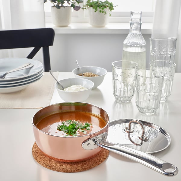Moderne keukentafel met koperen steelpan en roestvrijstalen deksel.
