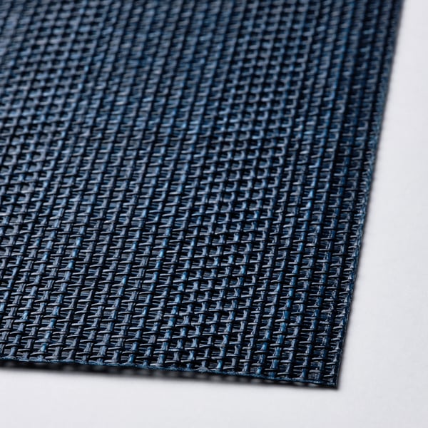 Een close-up van een donkerblauwe FLYGFISK placemat met textuur, met het dicht geweven plastic materiaal.