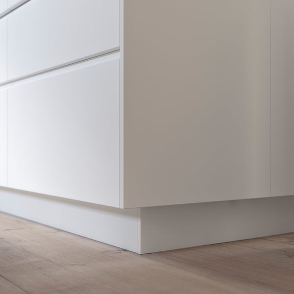 Witte FÖRBÄTTRA keukenkast, plint, houten vloer, modern minimalistisch design.