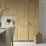 Moderne keuken met lichte houten FORSNÄS koelkast, stoel, vaas, theepot en boodschappen.