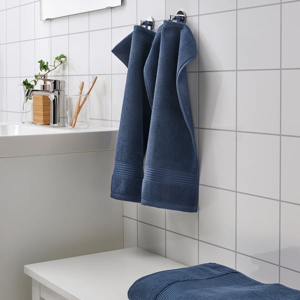 Blauwe FREDRIKSJÖN handdoeken: dik, zacht, 100% katoen. Hangt naast de wastafel in de badkamer, groter dan de tandenborstelhouder.
