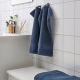 Blauwe FREDRIKSJÖN handdoeken: dik, zacht, 100% katoen. Hangt naast de wastafel in de badkamer, groter dan de tandenborstelhouder.