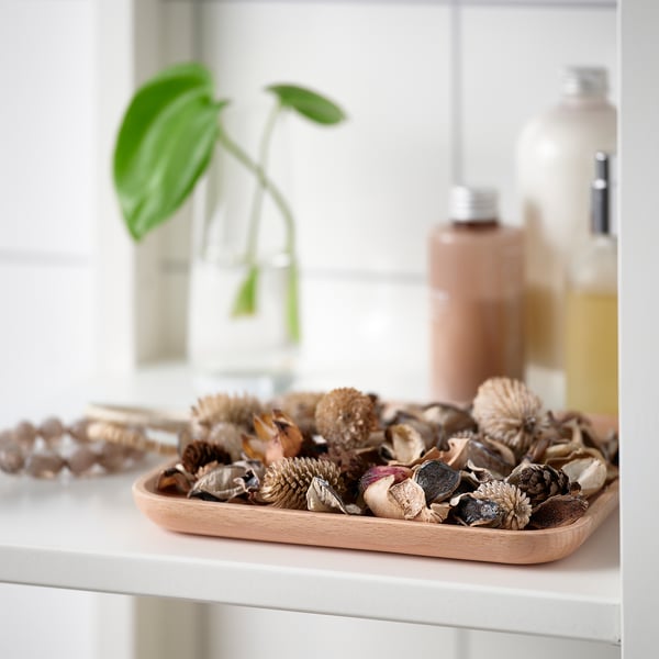 Houten dienblad bevat gedroogde bloemen en dennenappels, onderdeel van de inrichting van het huis.