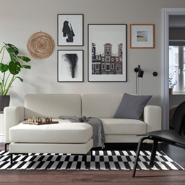 Moderne woonkamer met bank, schaakspel, kleed, kunstmuur, lamp, plant.