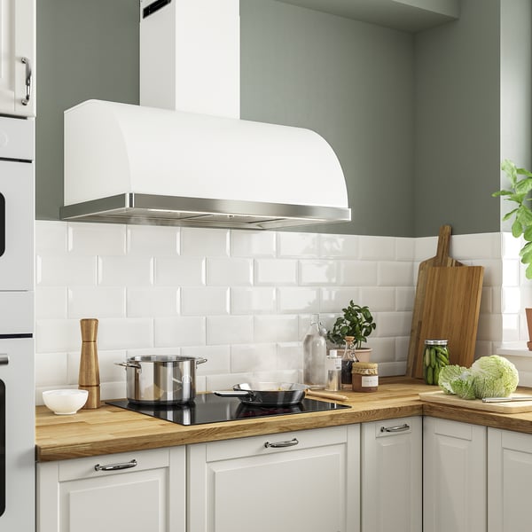 Moderne keuken met grote afzuigkap boven zwarte inductiekookplaat en houten aanrechtbladen.