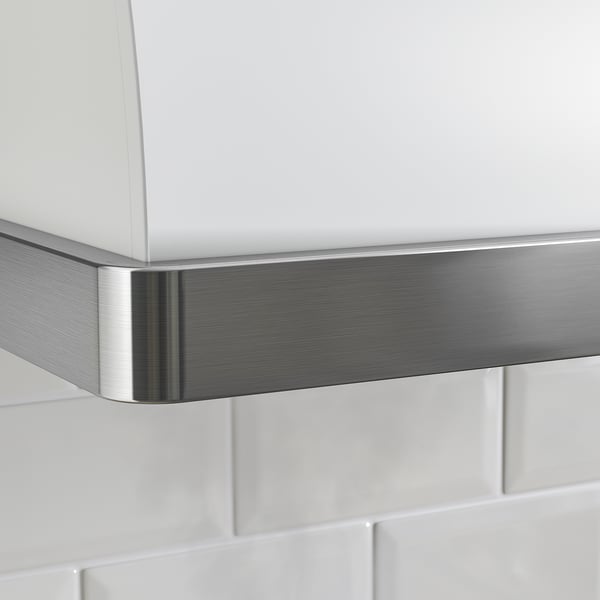 Roestvrijstalen en witte afzuigkap is gemonteerd tegen een wit betegelde muur. De slanke metalen bekleding benadrukt het moderne design.