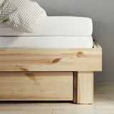 Houten bedframe, lichte natuurlijke afwerking, strak minimalistisch design.