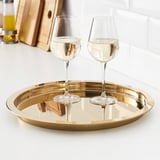 Twee wijnglazen op glanzend gouden dienblad, reflecterende omgeving, ideaal voor serveren en decoratie.