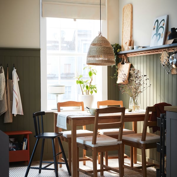 Gezellige keukentafel bij het raam met stoelen met kussens en bamboe dienblad.