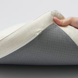 Een hand die een gedempte stoelbekleding optilt en de ritssluiting laat zien.