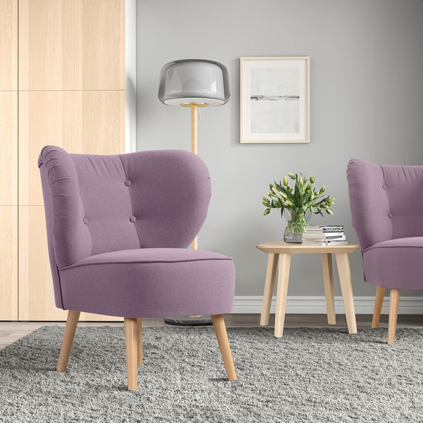 Moderne woonkamer met 2 paarse GUBBO fauteuils, lamp, bijzettafeltje, grijs vloerkleed en vaas met bloemen.