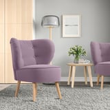 Moderne woonkamer met 2 paarse GUBBO fauteuils, lamp, bijzettafeltje, grijs vloerkleed en vaas met bloemen.