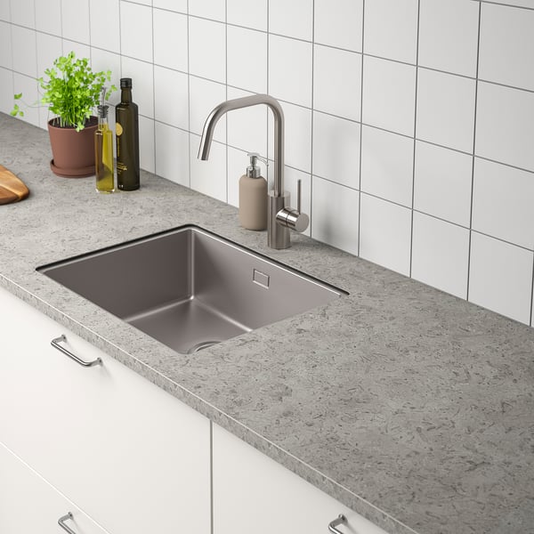 Metalen gootsteen met moderne kraan, zeepdispenser en aanrechtartikelen.