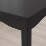 Close-up van een stijlvolle, moderne zwarte houten tafel met gladde afwerking en stevige randen.