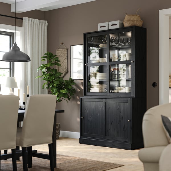 Donker houten dressoir met glazen deuren, decoratieve artikelen, kamerplant, stoelen.