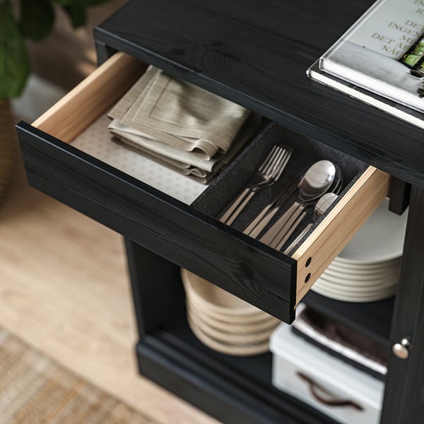 HAVSTA zwarte houten dressoirlade open, met bestek en doeken.