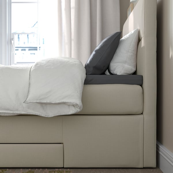 Bed met opberglades, zichtbaar onder de matras. Kussens en dekens kunnen er netjes in opgeborgen worden.