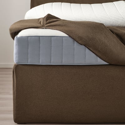 Bruin boxspringbed met opberglades. Afneembare, wasbare hoes. Grijze matras met gedessineerd hoofdkussen.