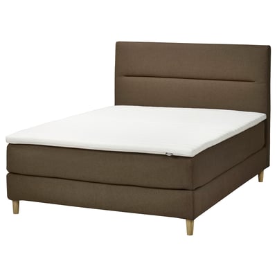 Een modern olijfgroen boxspringbed met een witte matras. Het heeft een zacht, gestoffeerd hoofdeinde en houten poten.