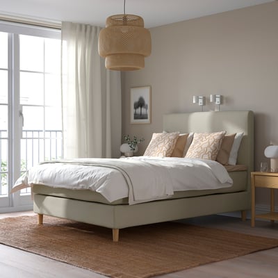 Modern groen HEMFJÄLLET boxspringbed met kussens, hanglamp, raam, nachtkastje en vloerkleed.
