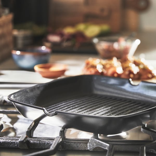 Grillpan met geribbeld oppervlak staat op een gasfornuis, klaar om te koken. Antiaanbaklaag voor het gemakkelijk losmaken en schoonmaken van voedsel.