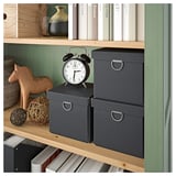 Een HEMNES boekenkast in een rustgevende groengrijze tint met gebeitste houten planken. Het toont decoratieve voorwerpen, boeken en opbergdozen op de planken.