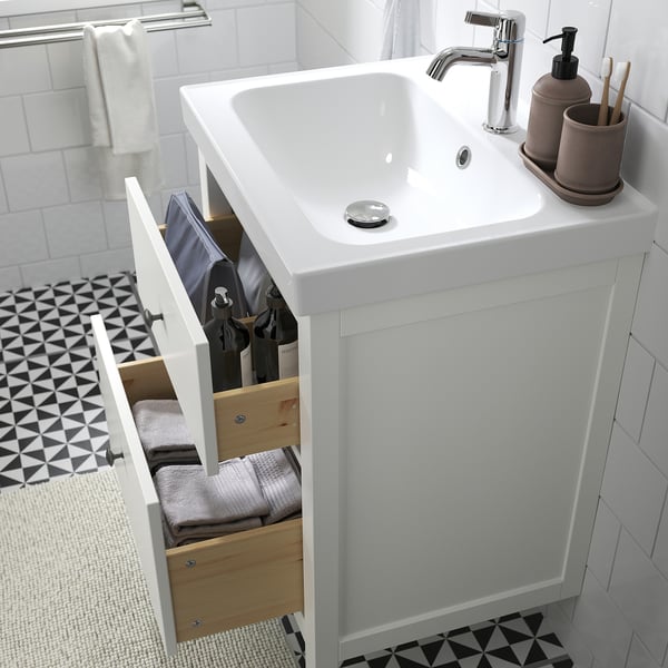 Modern badkamermeubel met lade met handdoeken en toiletartikelen, wit aanrechtblad en chromen kraan.