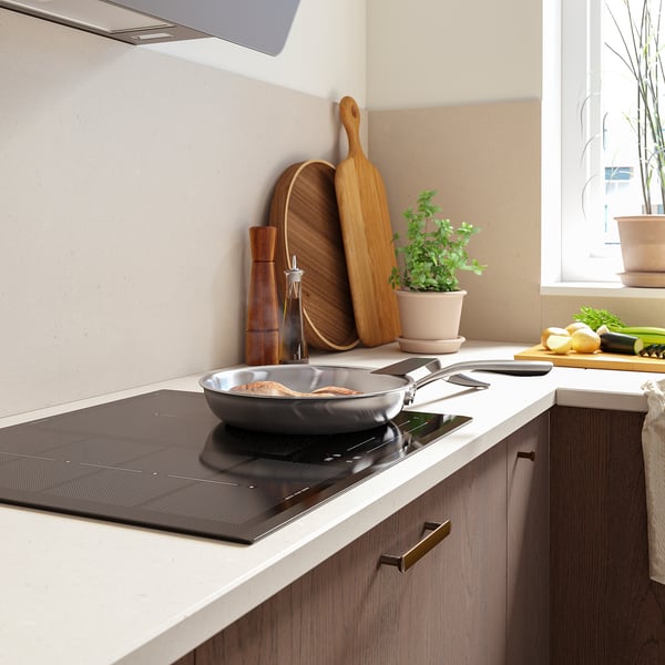 Moderne keuken met inductiekookplaat, koekenpan, houten keukengerei en verse producten.