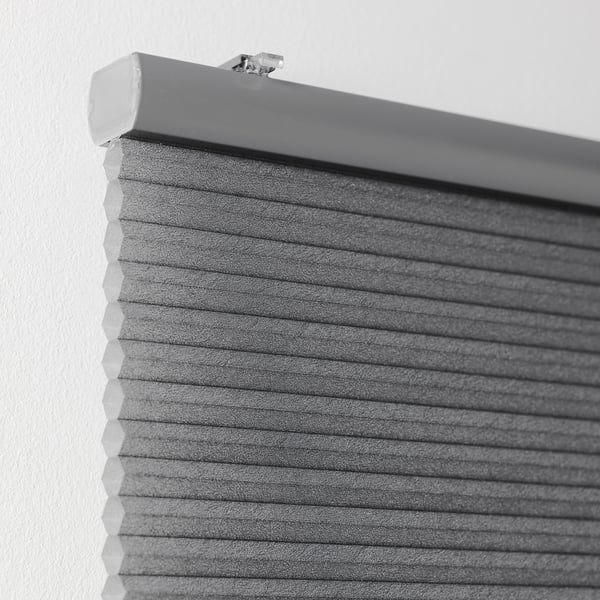 Grijze honingraatjaloezieën gemonteerd aan de muur, met celmateriaal voor isolatie en lichtblokkering.