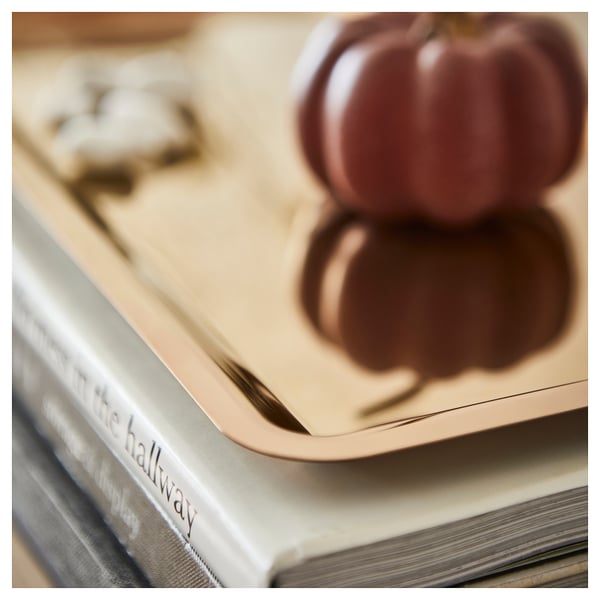 Reflecterende gouden schotel bovenop boeken met een wazige pompoen, die kwaliteit en stijl uitstraalt.