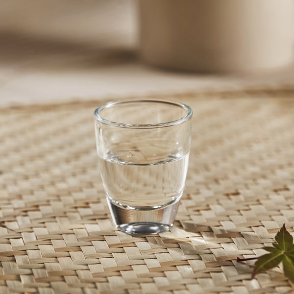 Klein glas op mat, perfect voor sterke dranken.