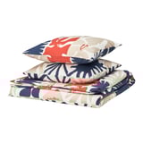 HYLSNEJLIKA beddengoedset, met gedurfde bloemmotieven in rood, marineblauw en beige op opgevouwen dekbed en kussenslopen.