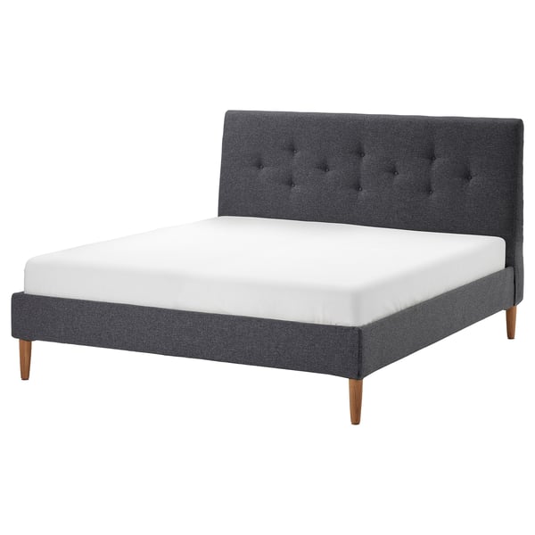 Donkergrijs IDANÄS bedframe met getuft hoofdeinde, houten poten en witte matras.