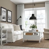 Moderne woonkamer met witte salontafel en bloemen.