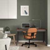 Modern kantoor aan huis met IDÅSEN bureau, groene kamer, oranje stoel, laptop, lamp en inrichting.