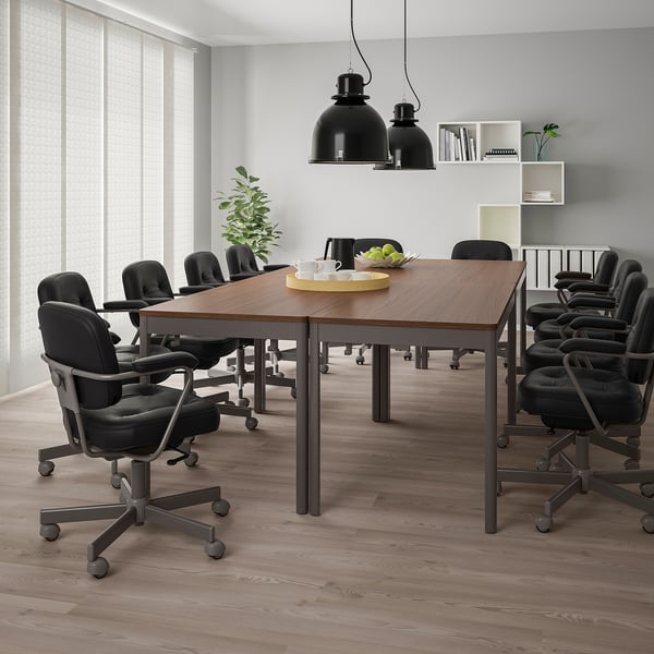 Modern kantoor met IDÅSEN-tafels en zwarte stoelen, hanglampen, groen en fruitschaal.