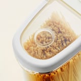 Doorzichtige plastic container met twee compartimenten gevuld met pasta, op elkaar gestapeld.