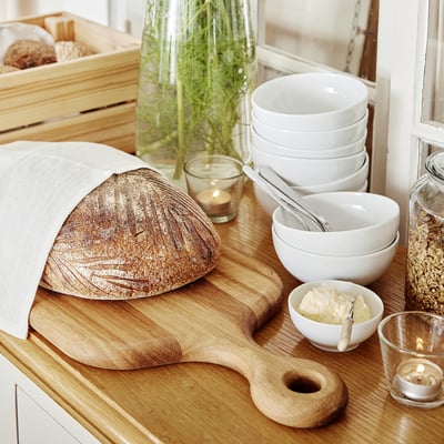 Ontbijtscène met rustiek brood, kommen en kaarsen op houten oppervlakken.