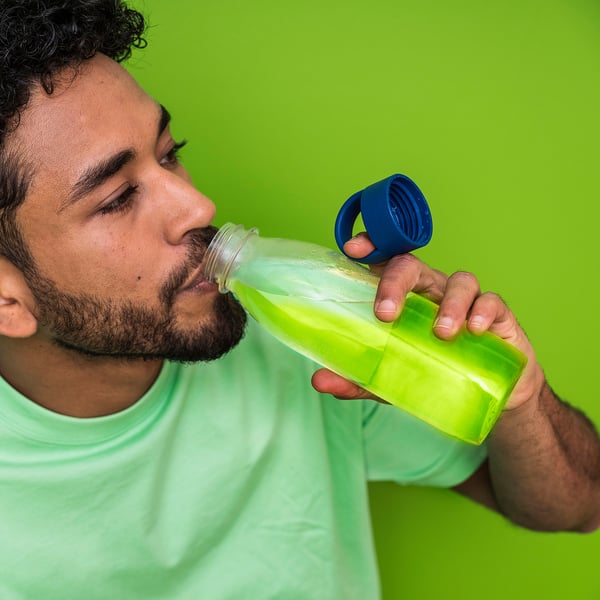 Man drinken uit groene IKEA 365+ waterfles met blauw deksel.
