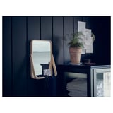 IKORNNES spiegel op donkere kast, reflecterend raam, met plant en gevouwen items.