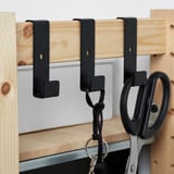 Houten plank met zwarte haken; Sleutels en schaar hangen.