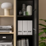Boekenplank met diverse spullen, waaronder boeken, witte dozen, vazen en een lamp.