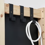 Een houten plank met drie zwarte haken met daarin een witte kabel.