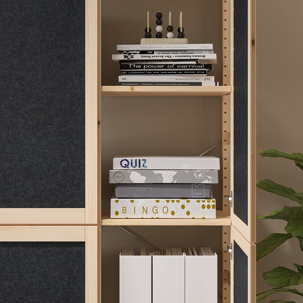 Een lichte houten boekenplank bevat diverse spellen en boeken. Functioneel opbergmeubel met verstelbare legplanken.