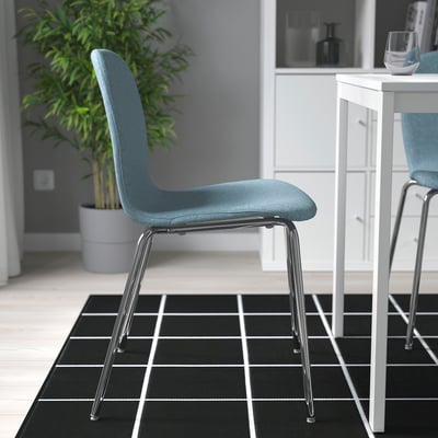Zwart-wit geruit tapijt met twee blauwe stoelen en een witte tafel. Eén stoel is iets gedraaid voor extra comfort.