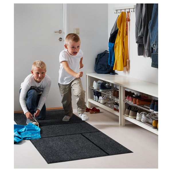Kinderen spelen in een lichte entree met KÖGE-mat, schoenenrek en hangende jassen.