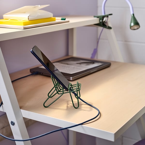 Op een wit bureau staat een groene KRUBBET mobiele telefoonhouder met een tablet, een laptop en notebooks.